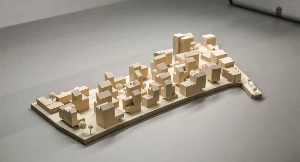 Architekturmodell Stadtquartier – Blockstruktur aus Holz mit abstrahierten Baukörpern und vereinzelten Bäumen, städtebauliche Übersicht.
