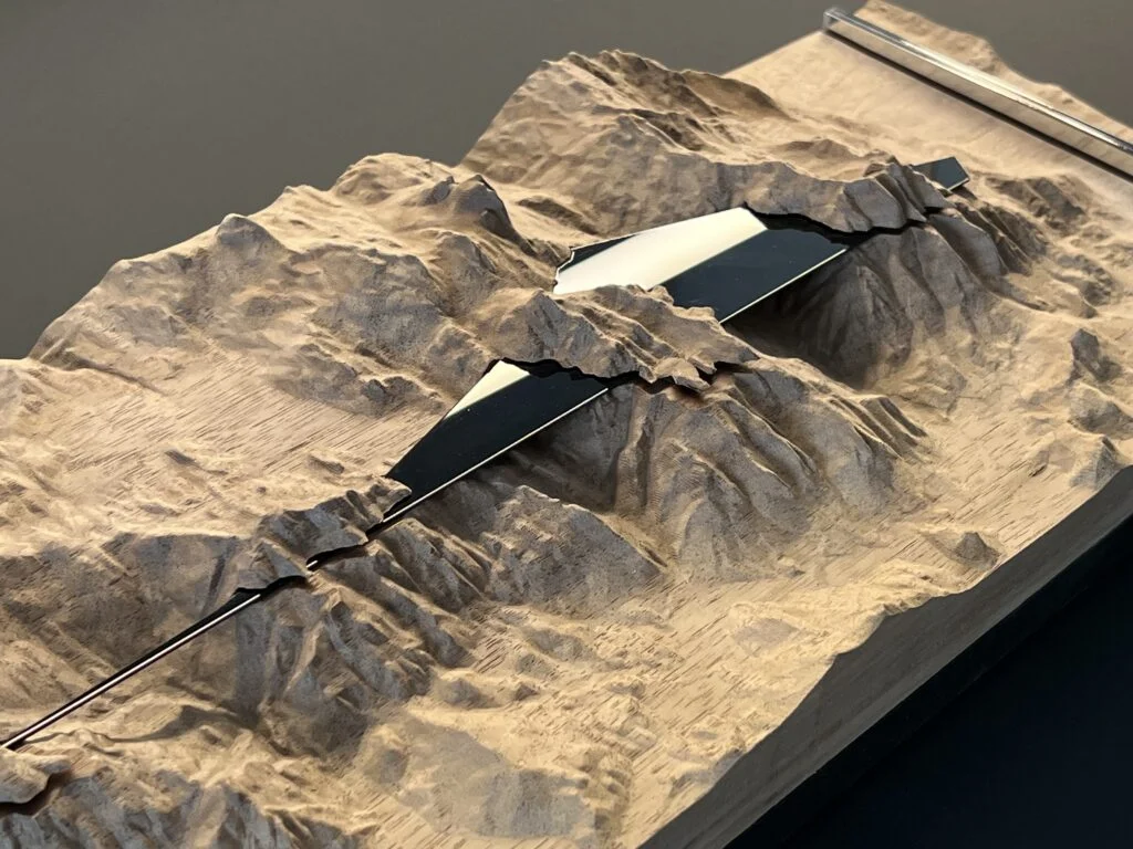Architekturmodell Holz – plastische Berglandschaft mit integriertem schwarz-weißem Volumenkörper in der Mitte.