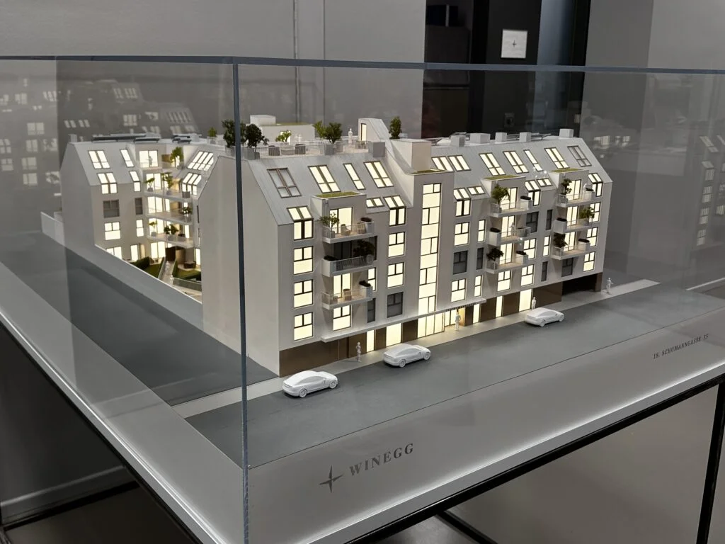 Architekturmodell Wien – Immobilienmodell im Maßstab 1:100, Wohnhaus mit beleuchteten Fassaden, Balkonen, Dachgärten und Acrylglas Vitrine.