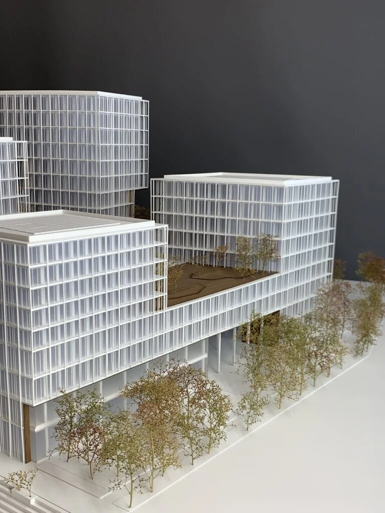 Homogenes Architekturmodell – Büro- und Wohnhochhäuser mit Rasterfassaden, Sockelzone auf Stelzen und Bäumen im Maßstab.
