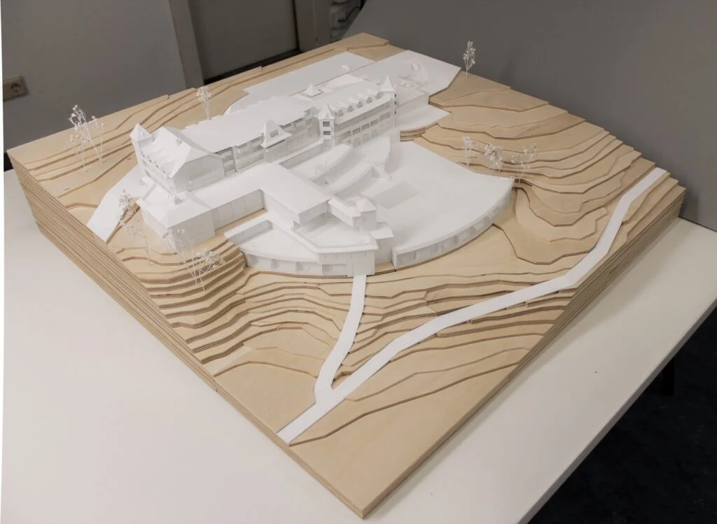 Architekturmodell Hotel 1:200 – Resort in Hanglage, weißes Gebäudemodell mit Holz-Topografie und abstrahierter Landschaft.