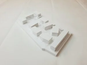 Weißes 3D-Druck Modell mit mehreren Baukörpern, städtebauliche Blockstruktur auf rechteckiger Grundplatte, präsentiert auf hellem Hintergrund.