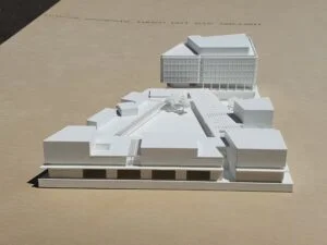 Weißes 3D-Druck Modell eines Gebäudekomplexes mit Innenhof und Platzgestaltung, präsentiert auf hellem Hintergrund.