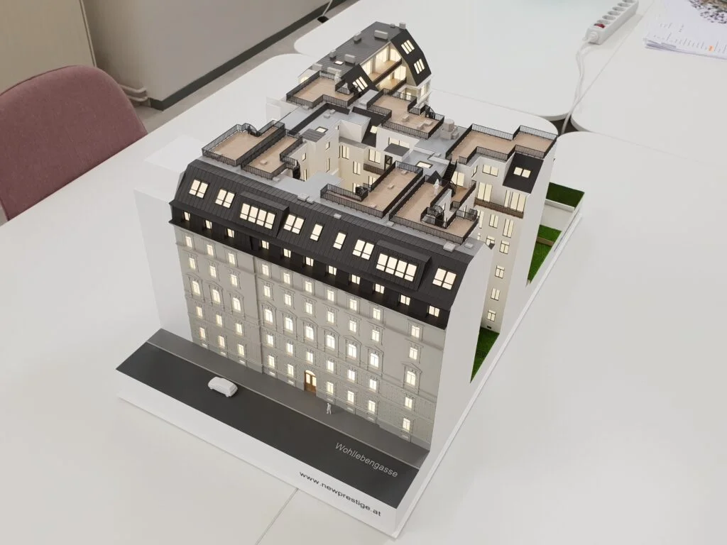 Immobilienmodell im Maßstab 1:200 – Wohngebäude mit modernem Dachausbau, beleuchteten Fenstern und Innenhof.