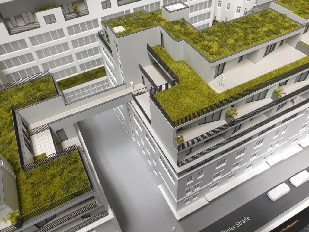 Architekturmodell – Wohnanlage mit begrünten Dachflächen und Steg zwischen zwei Gebäuden, Präsentationsmodell.