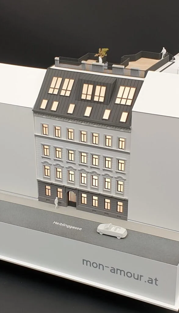 Immobilienmodell eines Wohnhauses im Maßstab 1:200 – saniertes Gebäude mit Dachterrasse und beleuchteten Wohnungen.