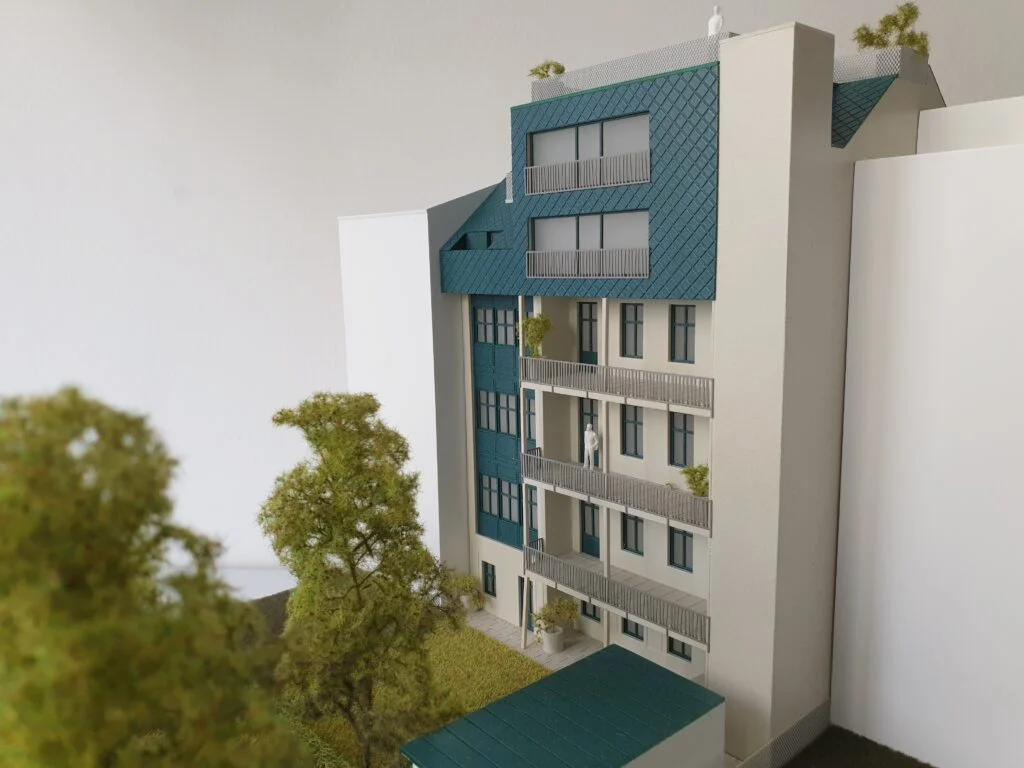 Architekturmodell 1:100 – Wohnhaus in Wien mit Balkonen, Dachausbau und begrüntem Umfeld.