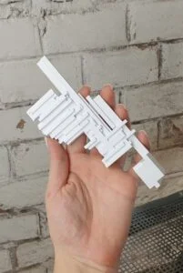 Bemusterungsmodell Architekturfragment weiß, in Hand gezeigt vor Ziegelwand, präzise Handarbeit aus Wien, ideal für Präsentationen.