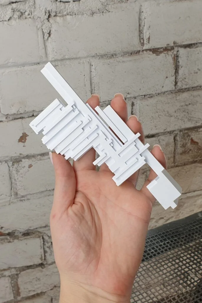 Bemusterungsmodell Architekturfragment weiß, in Hand gezeigt vor Ziegelwand, präzise Handarbeit aus Wien, ideal für Präsentationen.