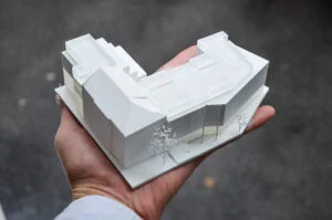 3D-Druck Architekturmodell 1:500 aus weißem Kunststoff, detailgetreu auf Handfläche präsentiert, ideal für Wettbewerbe und Präsentationen.