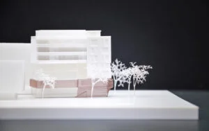 Architekturmodell im 3D-Druck aus weißem Kunststoff, Wohngebäude mit Fassadendetails und Bäumen im Vordergrund, Präsentation auf schwarzem Hintergrund