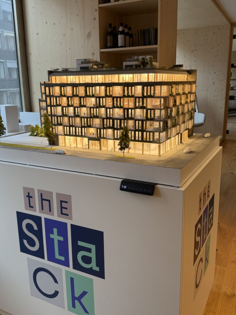 Beleuchtetes Architekturmodell eines mehrgeschossigen Wohngebäudes mit abgerundeten Balkonen auf einem Präsentationssockel.