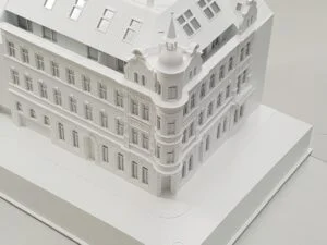 Architekturmodell einer historischen Fassade im Maßstab 1:100 mit detaillierten Ornamenten und Eckturm, komplett in Weiß.