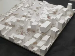 Städtebauliches Weißmodell mit klaren Baukörpern, farbigen Vegetationselementen und präziser Straßenstruktur im urbanen Quartier.