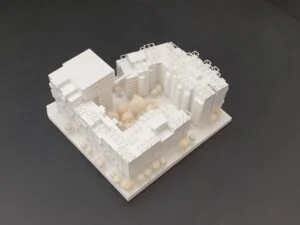 Wettbewerbsmodell einer weißen Wohnanlage mit zentralem Innenhof und umlaufenden Baukörpern in reduzierter Darstellung.