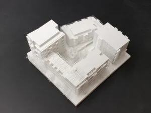 Wettbewerbsmodell in Weiß mit vier Baukörpern und zentralem Innenhof, klare Volumen und feine Fassadendetails.