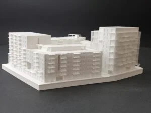 Wettbewerbsmodell eines Wohnquartiers mit mehreren Baukörpern und strukturierter Fassade auf dunklem Hintergrund.