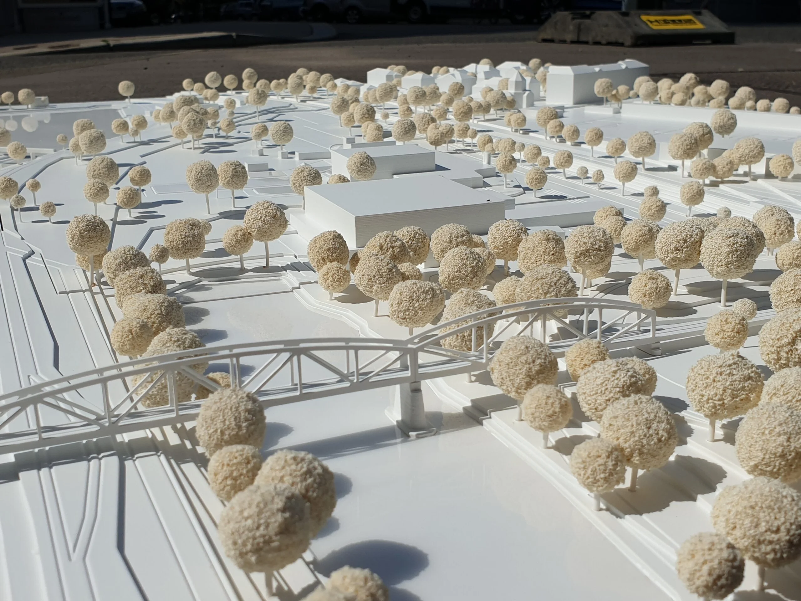 Weißes Umgebungsmodell mit Brückenkonstruktion, Verkehrsstrukturen und dichter Baumlandschaft.