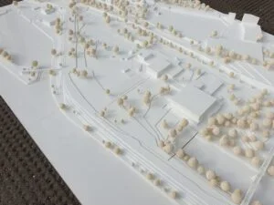 Weißes Umgebungsmodell mit Verkehrslinien, Geländeabstufungen und hellen Modellbäumen in großzügiger Anordnung.