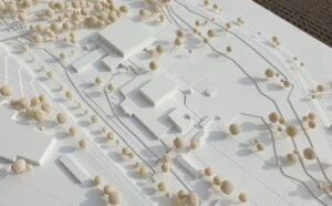 Umgebungsmodell mit hellen Modellbäumen, Verkehrsachsen und klar ausgearbeiteten Baukörpern im Weißmodell.