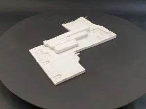 Weißmodell einer Sport- und Freianlage mit Spielfeld, Wegen und abstrahierten Gebäudestrukturen.