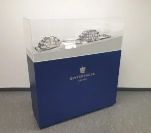 Ausstellungspodest mit Markenlogo und Acrylglasvitrine für Architekturmodell