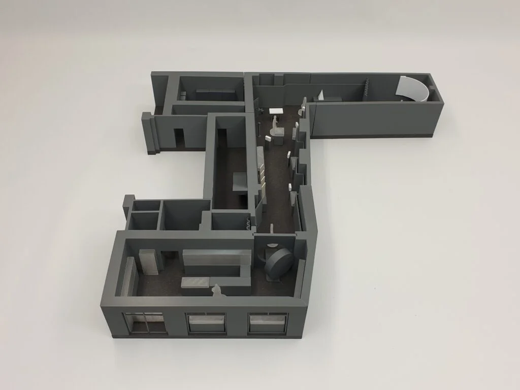 3D-Interieurmodell eines Bürogrundrisses mit Räumen, Möbeln und Arbeitsbereichen in grauer Ausführung von oben betrachtet.