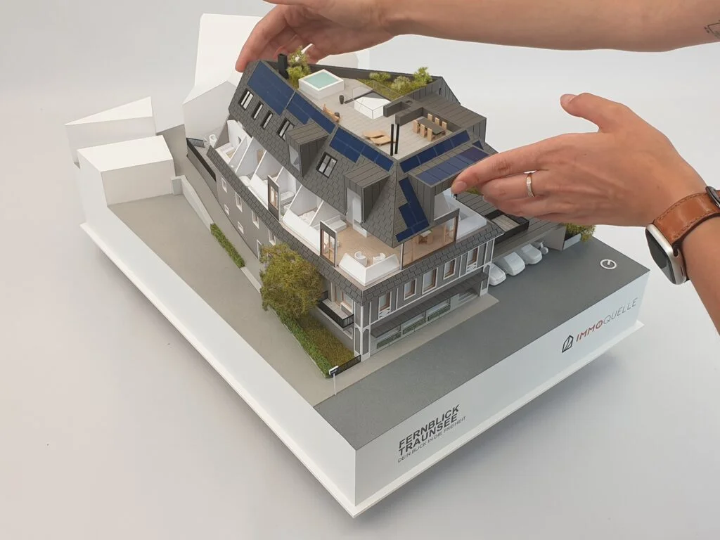 Abnehmbares Dach eines Architekturmodells – Darstellung der Innenräume und Funktion durch Hände einer Person.