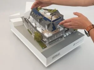 Abnehmbares Dach eines Architekturmodells – Darstellung der Innenräume und Funktion durch Hände einer Person.