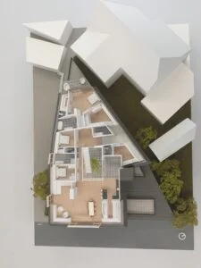 Dachgeschoss-Modell mit detaillierter Innenraumdarstellung und möbliertem Grundriss in dreieckiger Gebäudeform.