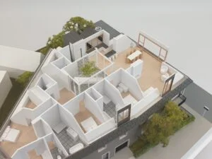 Schnittmodell einer Dachgeschosswohnung mit detaillierter Inneneinrichtung, Möbeln, Terrassenbereich und Treppenaufgang.