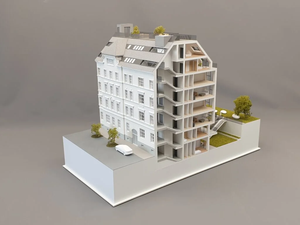 Architekturmodell im Schnitt mit sichtbaren Wohnungen, Treppenhaus, Dachgeschoss und begrünten Terrassen.