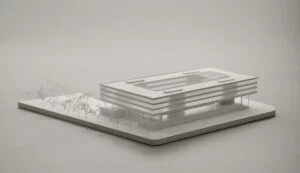 Weißmodell eines Flachbaus mit umlaufenden horizontalen Bändern und transparentem Dach im Präsentationskontext.