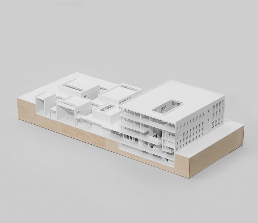 Weißes Architektur-Schnittmodell auf Holzsockel mit offenen Geschossen und Innenstruktur als Präsentationsmodell.