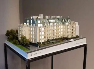 Beleuchtetes Immobilienmodell mit modernem Dachausbau, Grünflächen und detaillierter Fassadengestaltung.