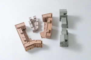 Architekturmodell in Einzelteilen – farbige Gebäudeelemente zur modularen Präsentation auf weißem Hintergrund