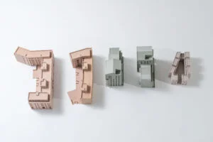 Draufsicht auf segmentierte Gebäudemodelle eines Wohnblocks mit verschiedenen Volumen und Farben auf weißem Hintergrund.