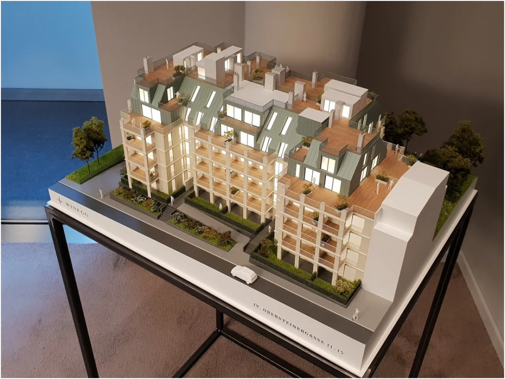 Architekturmodell eines modernen Wohnensembles mit gestaffelten Baukörpern, Dachterrassen und großzügigen Balkonen.