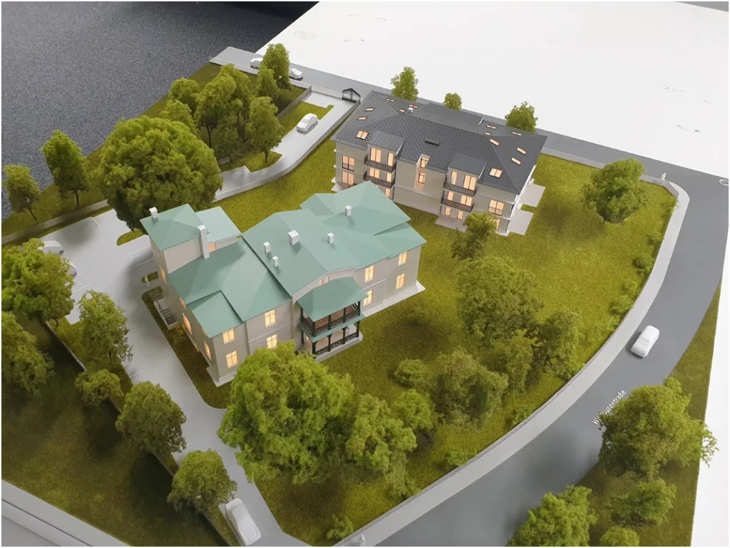 Architekturmodell eines Wohnensembles mit mehreren Gebäuden in parkähnlicher Grünanlage.