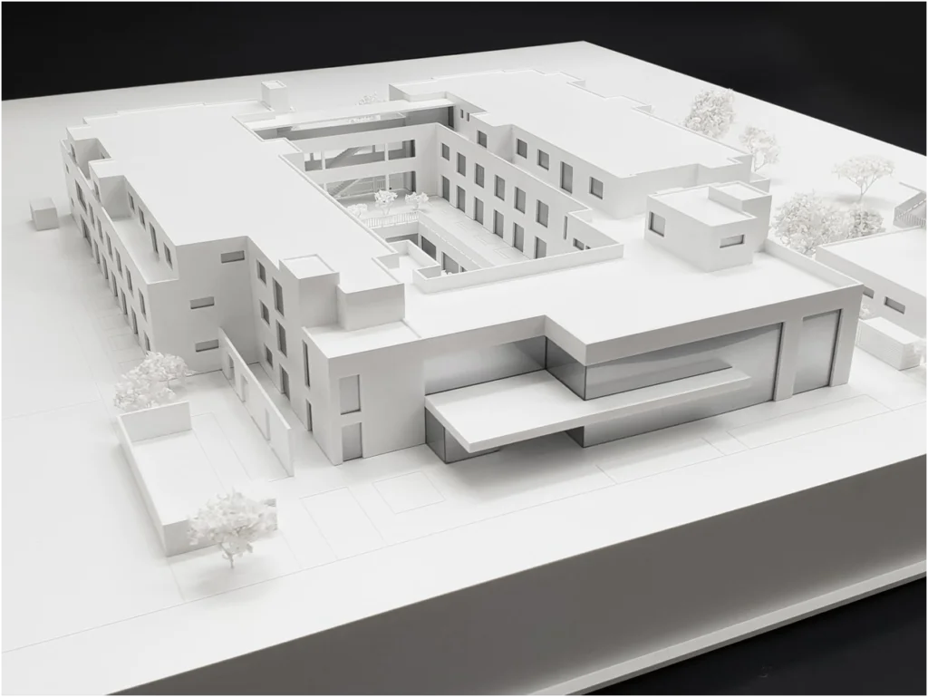 Weißes Immobilienmodell eines modernen Gebäudekomplexes mit Innenhof und klarer Kubatur