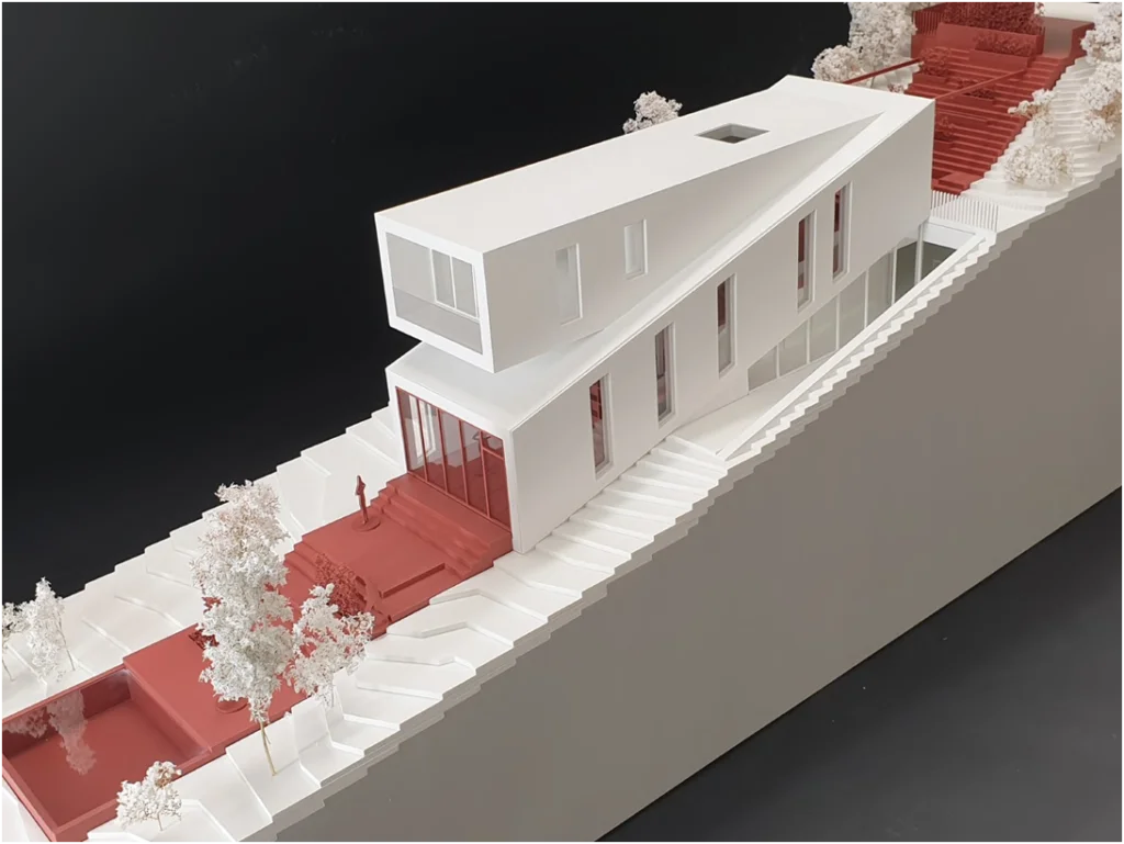 Architektur-Weißmodell eines modernen Gebäudes mit terrassierter Topografie und roter Funktionszone