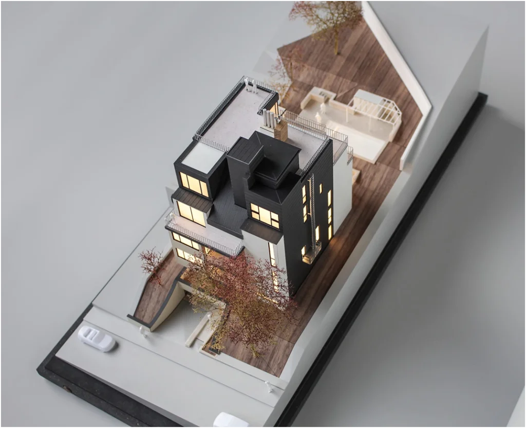 Architekturmodell eines Wohngebäudes mit schwarzem Dachaufbau, beleuchteten Fenstern und Außenraumdarstellung