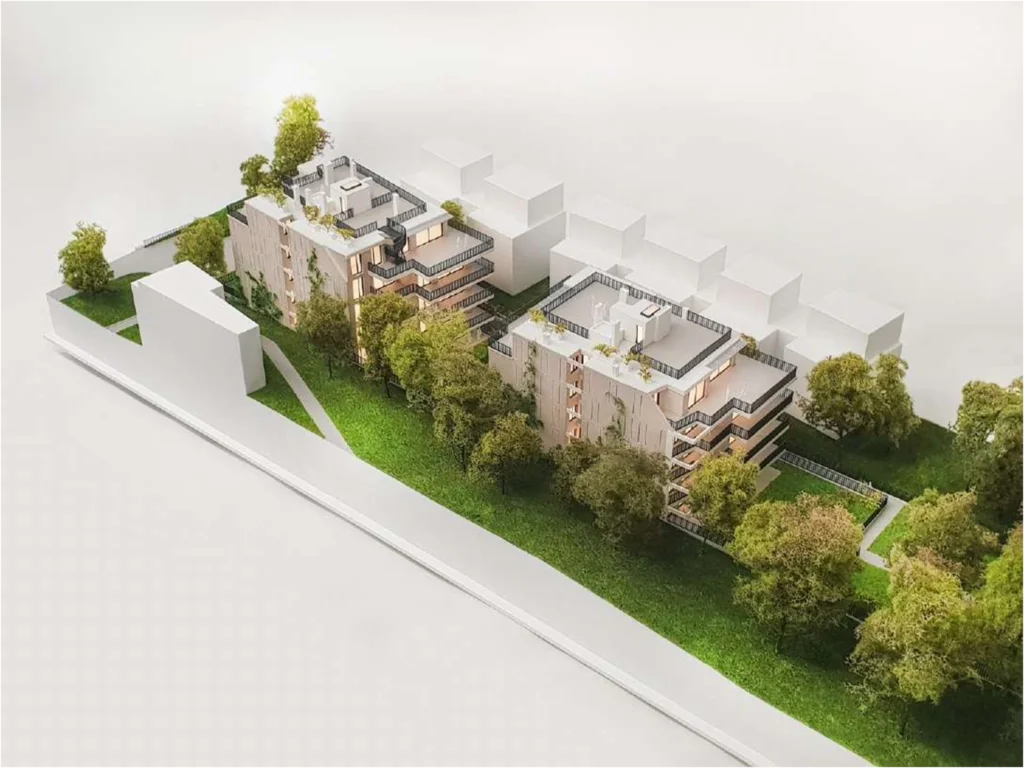 Hochdetailliertes Architekturmodell eines Wohnprojekts mit zwei Gebäudekörpern, begrünten Außenräumen und realistisch dargestellter Umgebung im Maßstab 1:100
