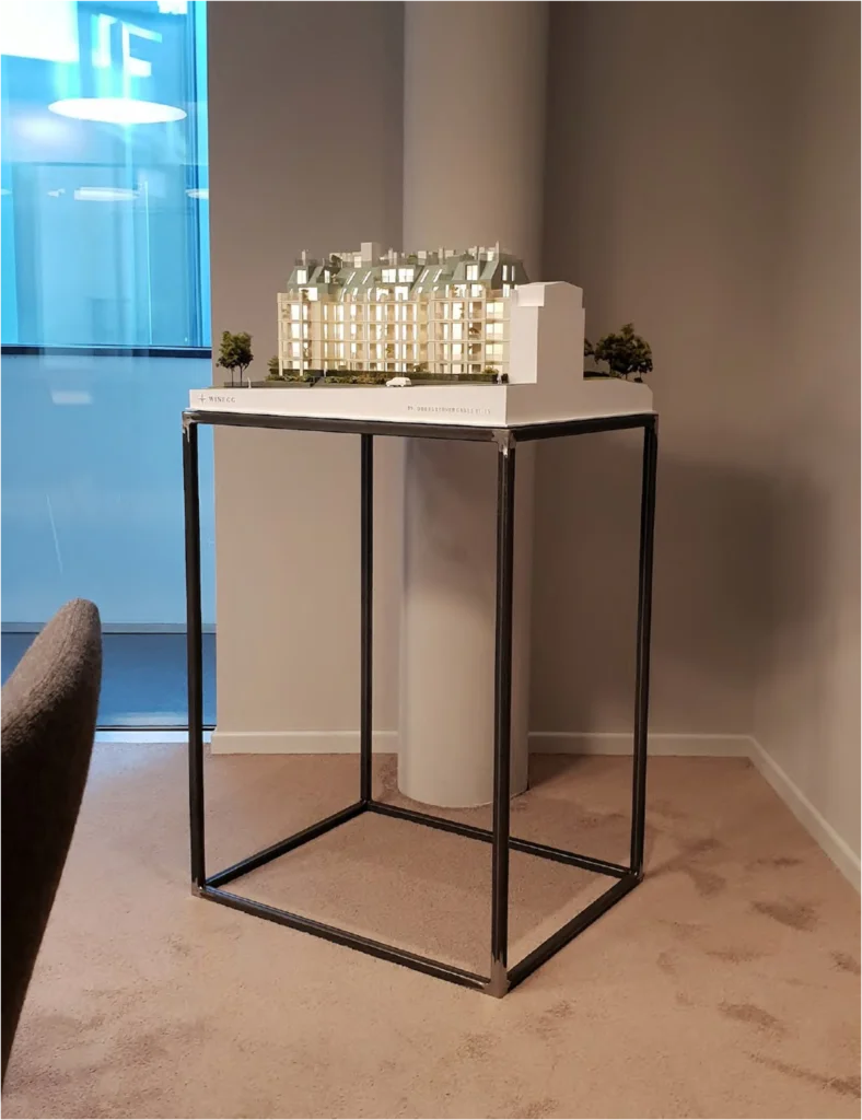 Hochdetailliertes Architekturmodell eines Wohngebäudes auf Präsentationspodest, realistische Fassadengestaltung und Beleuchtung für Projektpräsentationen
