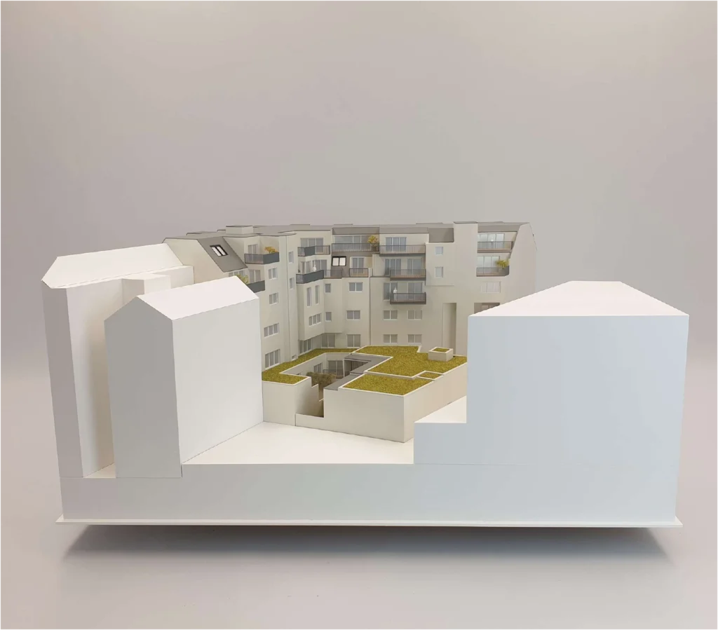 Architekturmodell M 1:100 – Innenhofperspektive eines Wohnprojekts mit DG-Aufstockung Innenhof-Ansicht eines Architekturmodells im Maßstab 1:100 – Wohnbau mit Dachgeschossausbau und begrüntem Innenhof