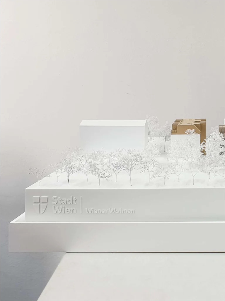 Architekturmodell mit integrierter Beschriftung „Stadt Wien | Wiener Wohnen“, Straßen- und Fassadenbeschriftung auf weißem Sockel, minimalistisches Stadtmodell