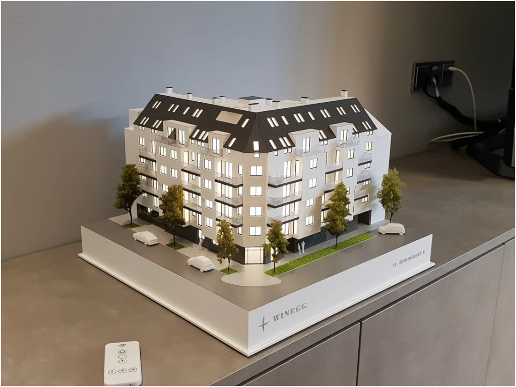 ochdetailliertes Immobilienmodell einer modernen Wohnanlage im Maßstab 1:100 mit präziser Darstellung von Balkonen, Loggien und Grünanlagen