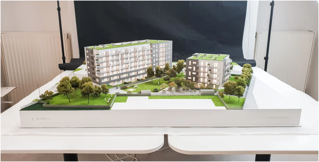Großflächiges Immobilienmodell eines modernen Wohnbauprojekts im Maßstab 1:100 mit LED-Beleuchtung und detaillierter Parkanlage