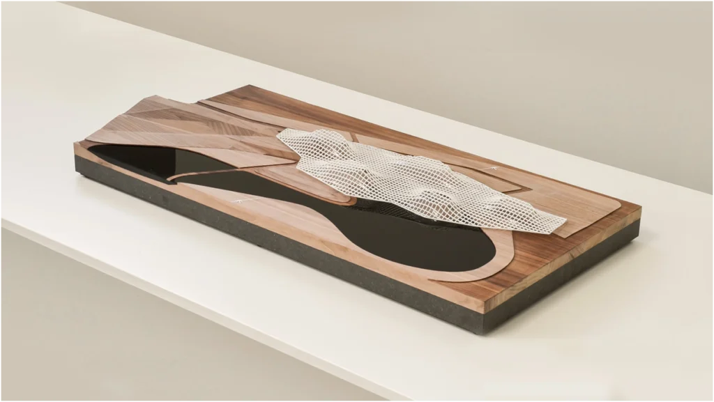Architekturmodell aus Holz mit topografischem Relief und abstrakter Bebauungsstruktur auf dunklem Sockel