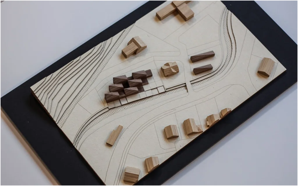 Städtebauliches Architekturmodell aus Holz mit abstrahierten Baukörpern, gelaserter Topografie und dargestellter Erschließungsstruktur